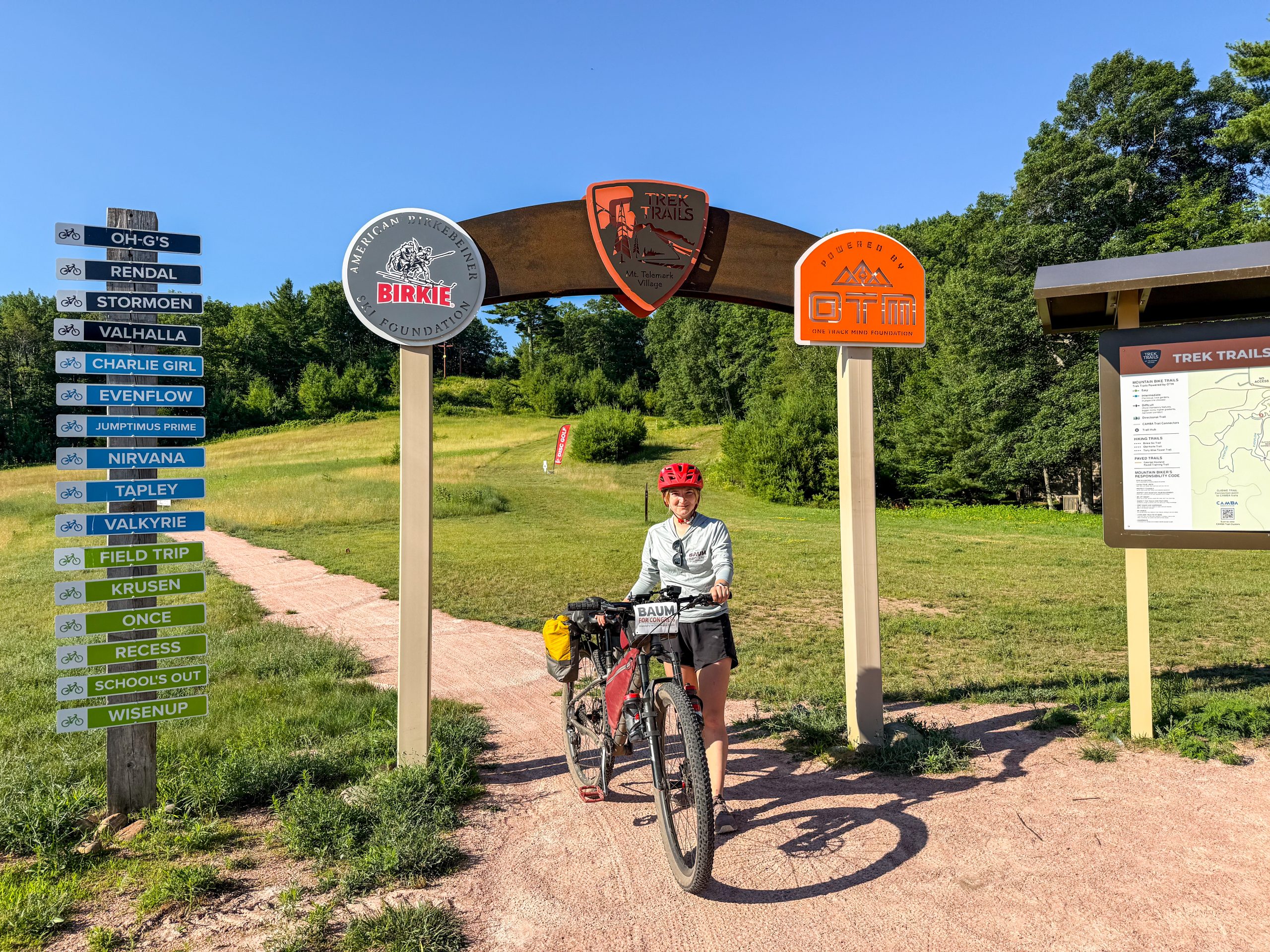 Niina Baum standing with a bike under the CAMBA trails sign